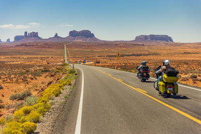 Rear view of man riding motorcycle on road