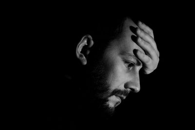 Close-up portrait of young man against black background