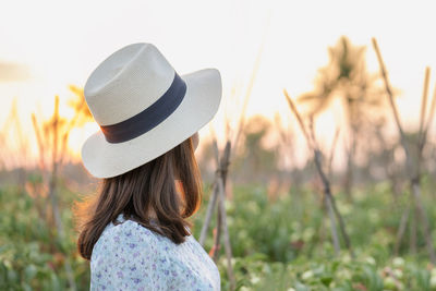 Rear view of woman with hat standing against plants