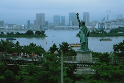 Statue of bridge over river against buildings in city