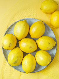 Directly above shot of lemons in plate against yellow background