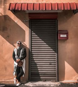 Full length of man wearing sunglasses standing against built structure