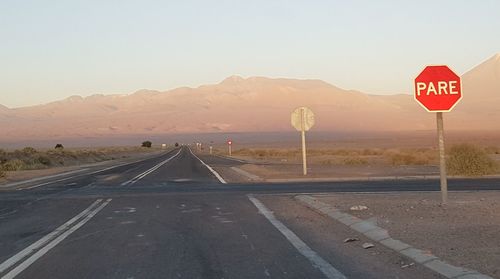 Road sign by mountains against clear sky