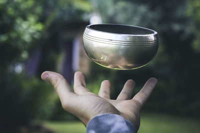 Close-up of hand holding cup against blurred background