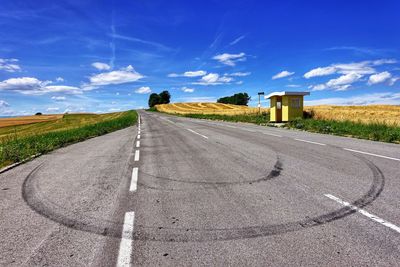 Road by landscape against blue sky