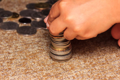 Close-up of hand stacking coins on carpet