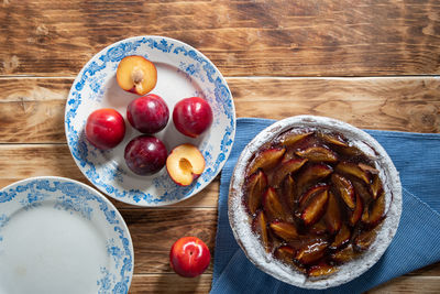 Glazed plum cake with fresh plums on a wooden table