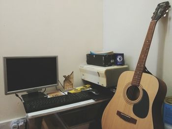 Guitar on table against wall at home