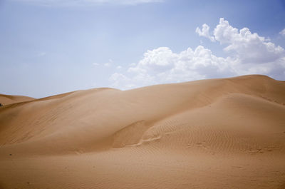 Scenic view of desert against cloudy sky