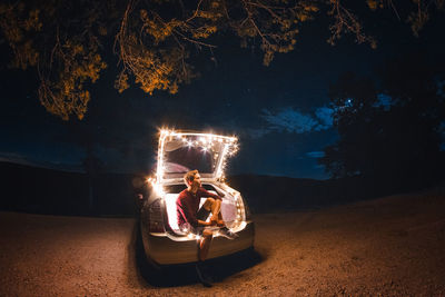 Man sitting in illuminated car at night