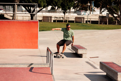 Man riding skateboard in urban street skatepark. casual guy wearing shorts and t-shirt.