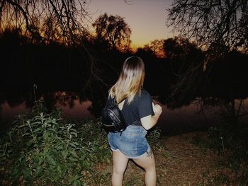 Rear view of woman standing by plants against sky