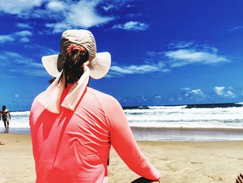Rear view of woman on beach against sky