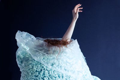 Woman in plastic bag against black background