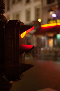 Close-up of hand against illuminated building at night