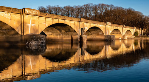 Arch bridge over river against clear sky