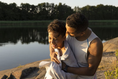 Father tickling son while wrapping him with towel during sunset