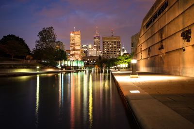 Canal by illuminated buildings against sky at night indianapolis 