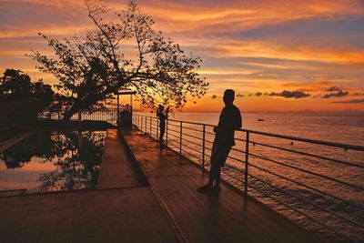 Silhouette man looking at sea against sky during sunset