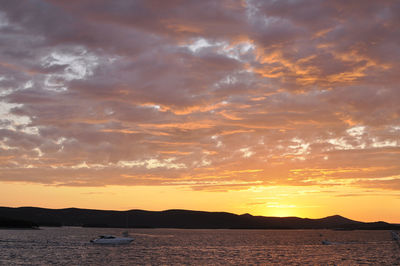 Scenic view of sea against cloudy sky during sunset