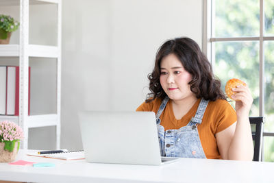 Portrait of woman using laptop while sitting on table