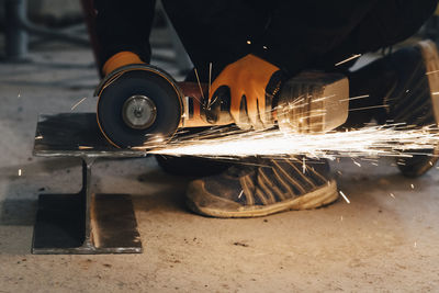 Male worker cutting metal using electric saw while working at construction site