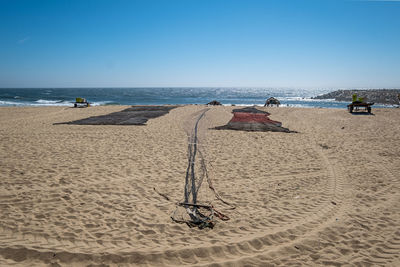 Scenic view of beach with fishing nets against clear sky