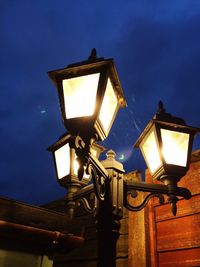 Low angle view of illuminated lamp post against blue sky