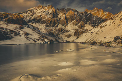 Scenic view of lake by snowcapped mountains against sky