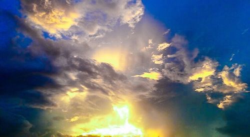 Low angle view of sunlight streaming through clouds