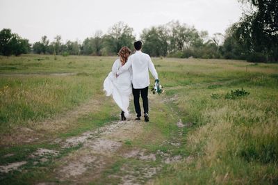 Rear view of couple walking on field