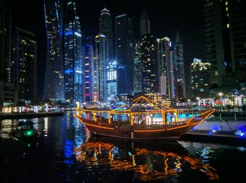 Illuminated modern buildings by river at night