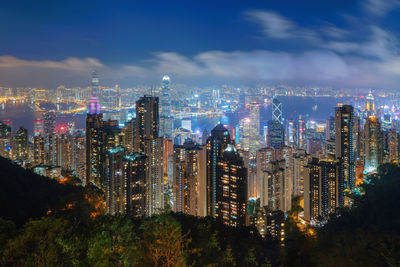 Aerial view of illuminated modern buildings in city against cloudy sky