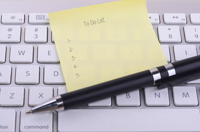 Close-up of pen with adhesive note on computer keyboard