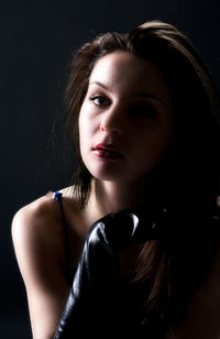 Close-up portrait of sensuous young woman against black background