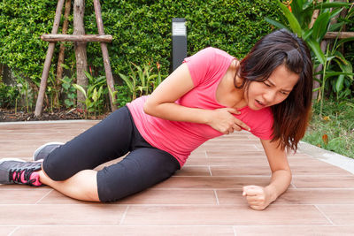 Woman suffering chest pain on hardwood floor in park