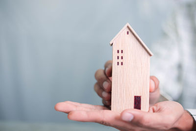 Close-up of hand holding toy against wooden wall