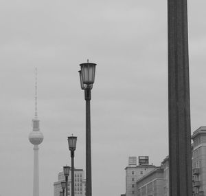 Low angle view of lamp posts and fernsehturm against sky in city