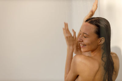 Side view of shirtless young woman against wall