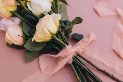 Close-up of roses tied with a pink ribbon on a pink table