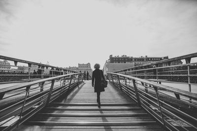 Rear view of woman walking on bridge in city