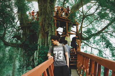 Woman standing on footbridge in forest