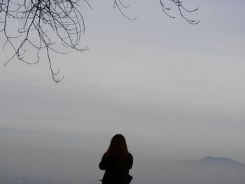 Rear view of woman standing against sky