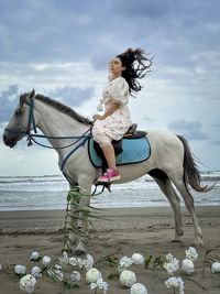 Rear view of woman riding horse against sky