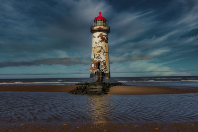 Lighthouse by sea against sky