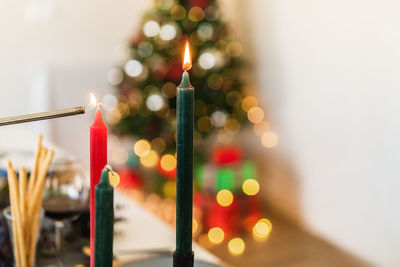 Bright wax candles with shiny flame on table during festive event on blurred background with bokeh effect