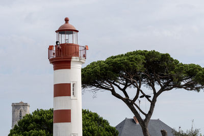 Lighthouse by sea against sky