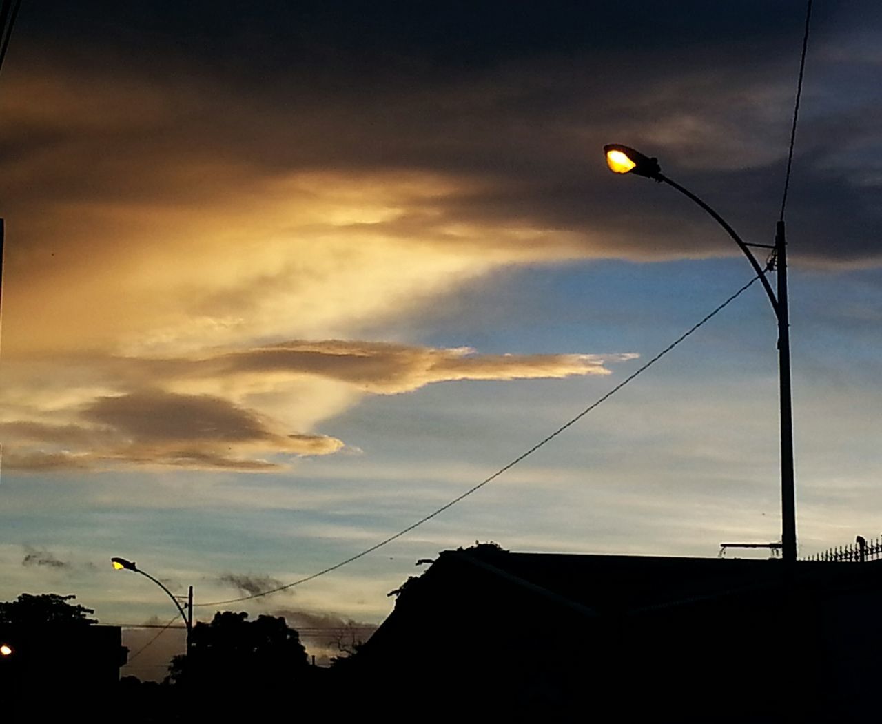 low angle view, architecture, building exterior, built structure, sky, street light, silhouette, cloud - sky, lighting equipment, power line, dusk, high section, cloudy, cloud, electricity, building, sunset, house, cable, moon