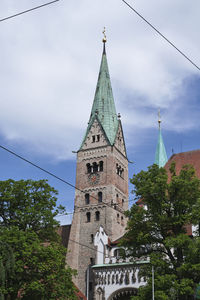 Low angle view of trees and building against sky