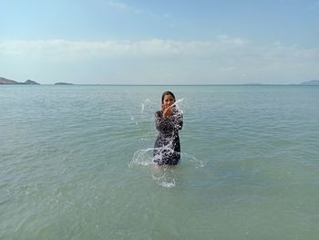 Young woman in sea against sky